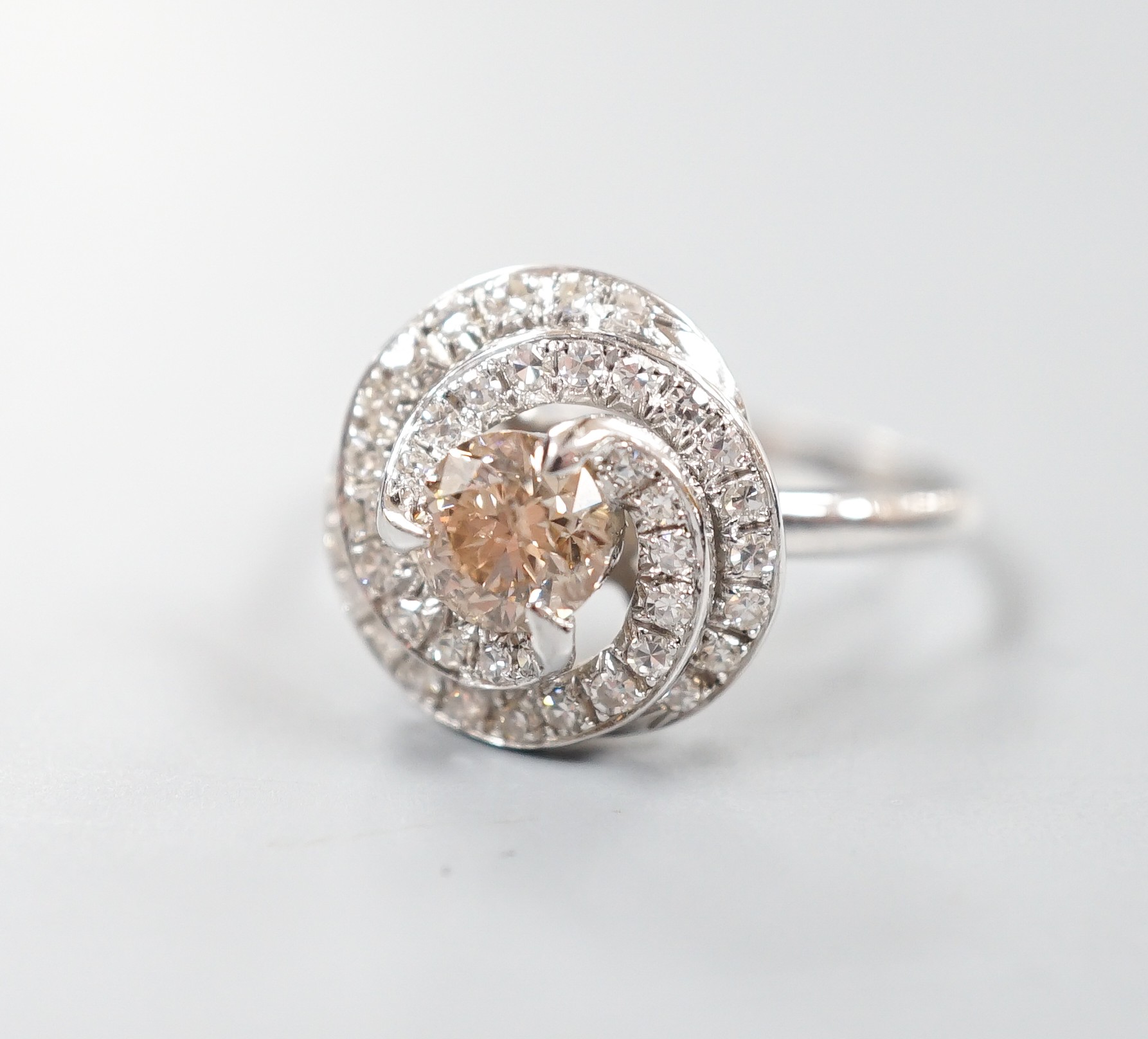 A French white metal(18ct poincon mark) and cognac coloured single stone diamond ring, with diamond set spiral cluster setting, size S, gross 5.5 grams.